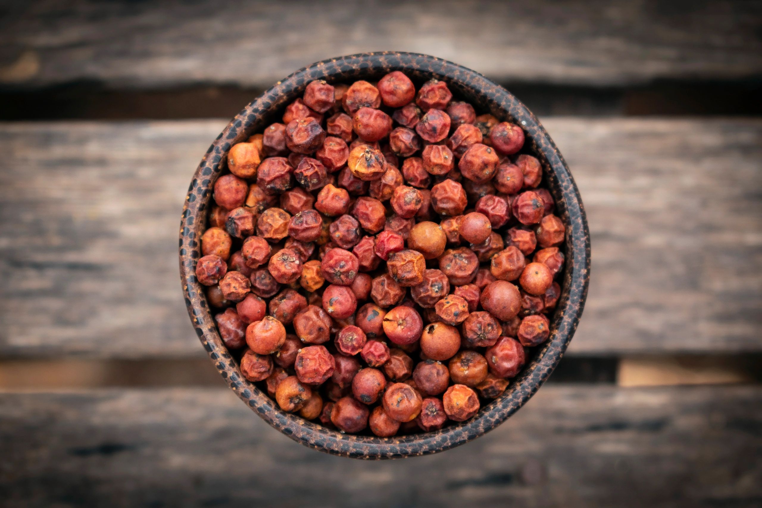 Dried red peppercorns in a wooden bowl